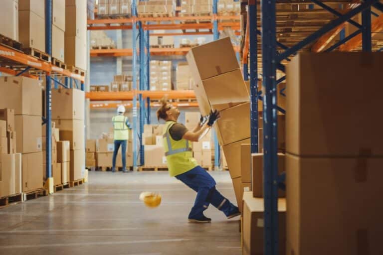Warehouse worker falling near stacked boxes, representing near-miss detection through logistics video analytics for improved safety.