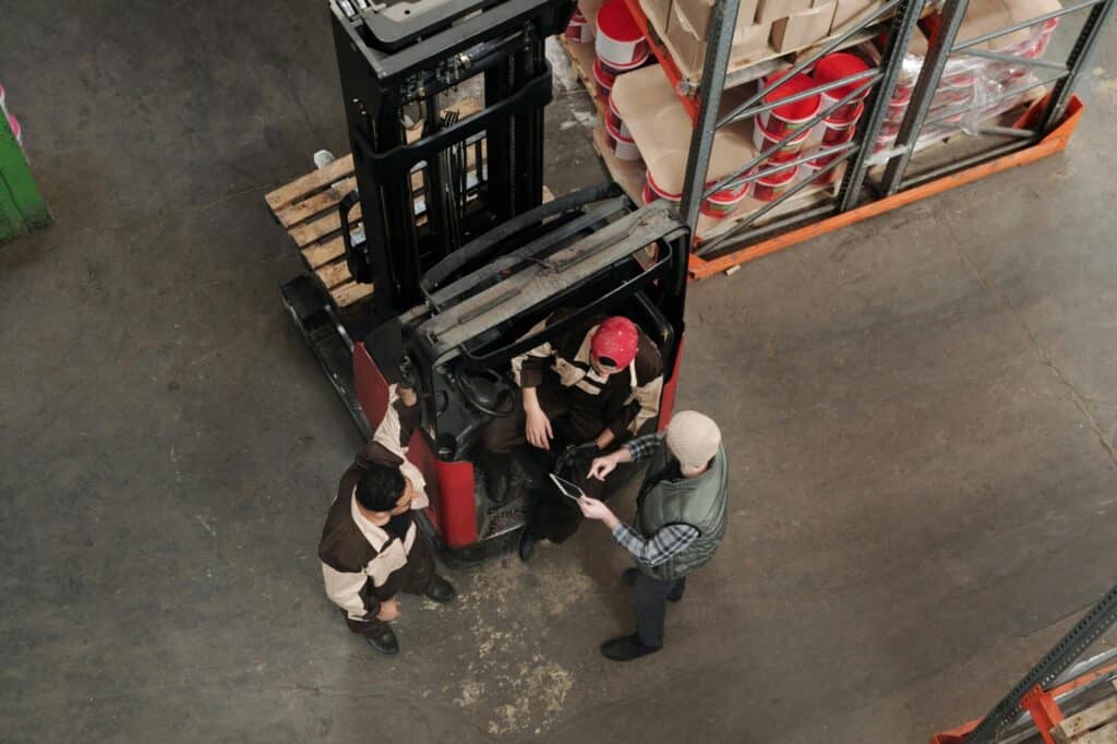 Warehouse employees standing and talking near goods, representing shrinkage and security lapse detection with logistics video analytics.