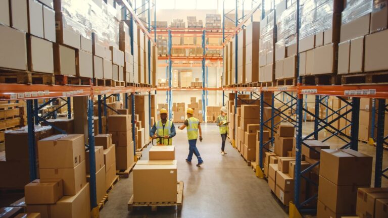 Warehouse aisle congested with workers and forklifts, showing workflow bottlenecks detected by logistics video analytics.